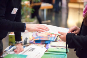 Man and Woman Sharing Information Leaflet over Exhibition Stand - Work in Switzerland